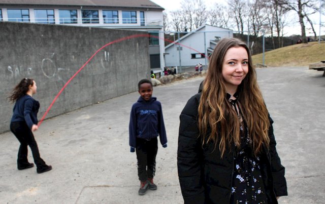 Portrett av Henriette tatt i skolegården med barn i bakgrunnen