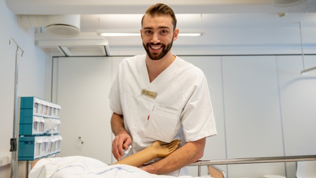 Gutt i sykepleieruniform øver på en dukke