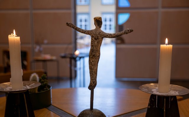 En krusifiks står på alteret med to tente lys