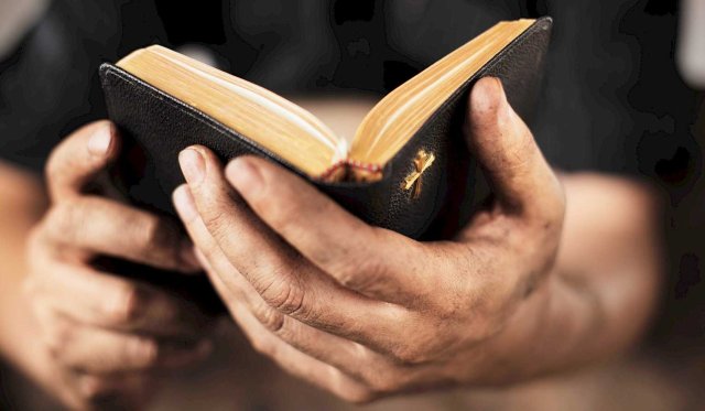 Hender holder en åpen bibel