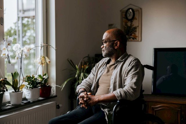 Mann sitter alene i en stol og ser ut vindu