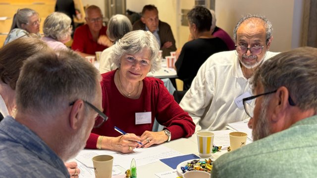 En gruppe eldre sitter rundt et bord og diskuterer