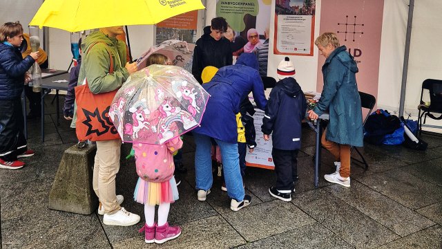 En gruppe mennesker står med ryggen til og ser på VIDs stand under forskningstorget.