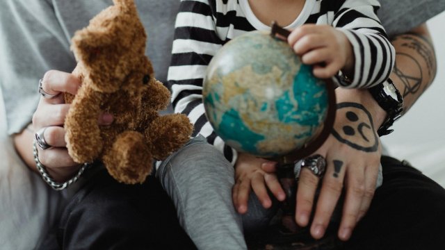 Et barn på fanget til en voksen med bamse og globus