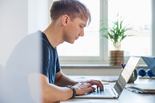 Ung mann skriver på et tastatur på en laptop