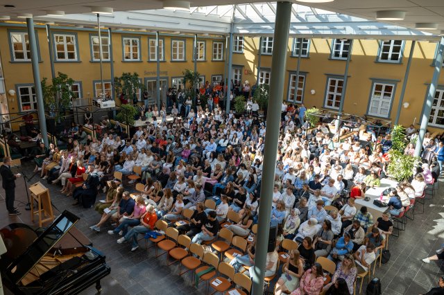Stor gruppe studenter sitter samlet til studiestartseremoni