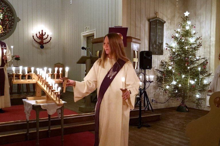 bilde av Kristina som tenner lys i en julepyntet kirke