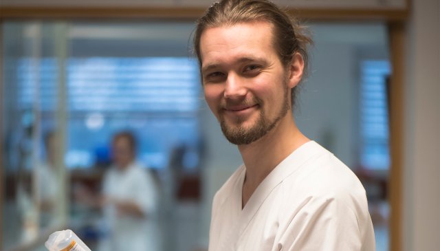 Portrett av Bjørn i sykehusuniform i sykehusmiljø