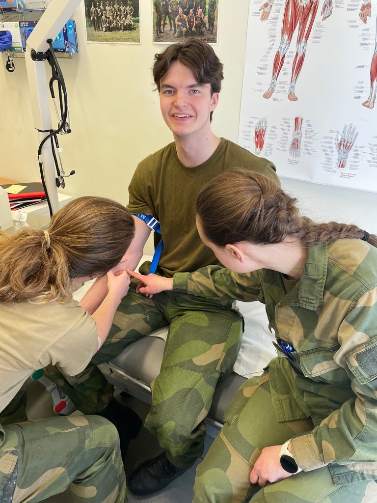 Kjartan får satt veneflon av to jenter i militæruniform