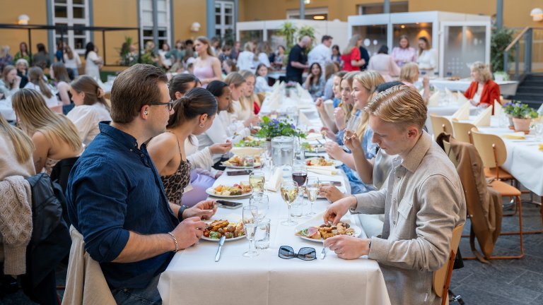 Atriet fylt med studenter som spiser en fin middag