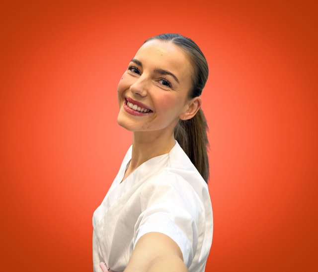 Jente med mørkt, langt hår ser i kamera og smiler