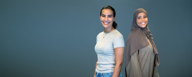 To jenter ser i kamera og smiler