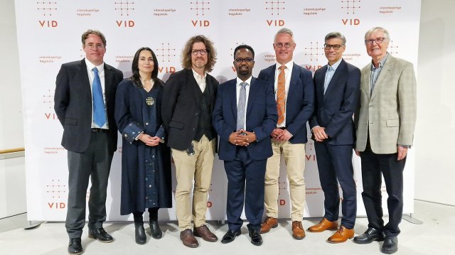 group photo taken in front of a backdrop with VID logos