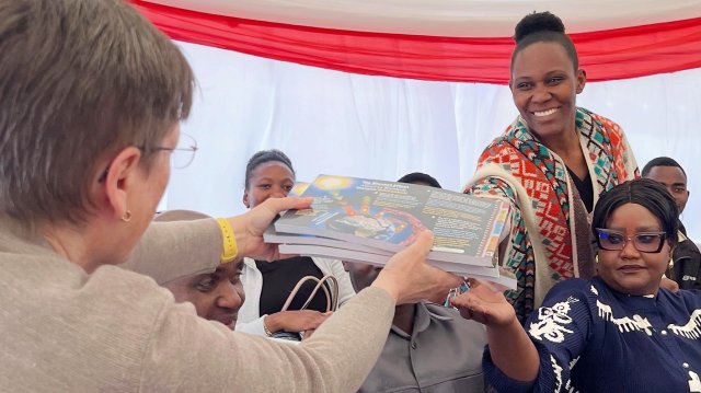 A woman gives a few copies of a book to another woman