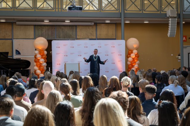 Rektor taler foran en stor gruppe studenter