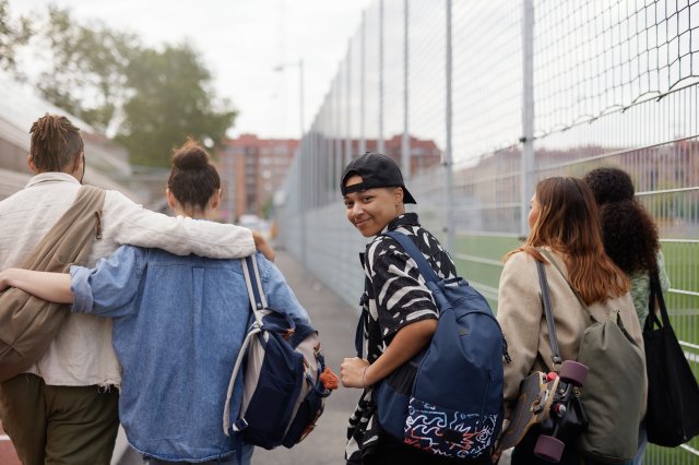 Fem ungdommer som går utendørs. En snur seg og ser i kameraet