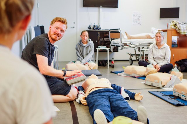 Studenter får demonstrert bruk av hjertestarter på øvingsdukke