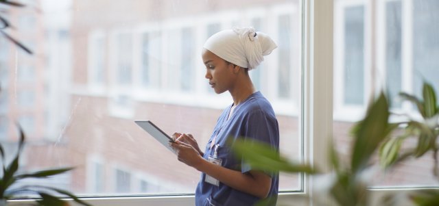 Sykepleierstudent i uniform leser å en iPad
