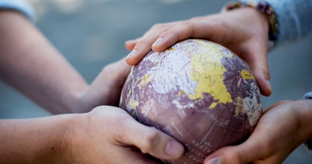 Barnehender som holder en liten jordklode