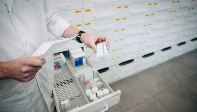 En apoteker tar ut en pilleeske fra en skuff
