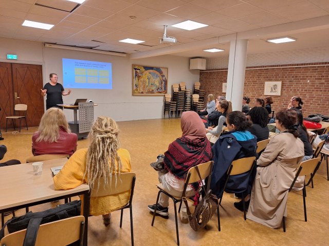 Deltakere sitter og følger en forelesning i et klasserom