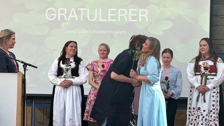 Student får klem og rose av lærer på scena.