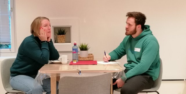 To personer sitter og snakker ved et bord