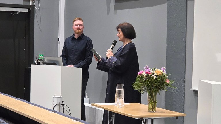 Nenningsland står på scene ved siden av Leis-Peters som snakker i mikrofon