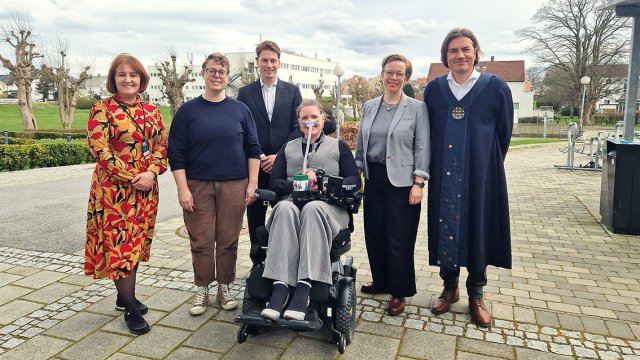 Portrett av dem alle stående samlet utendørs. 