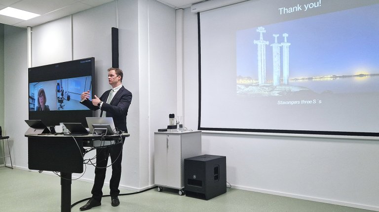 Edebol står og presenterer foran skjerm. 