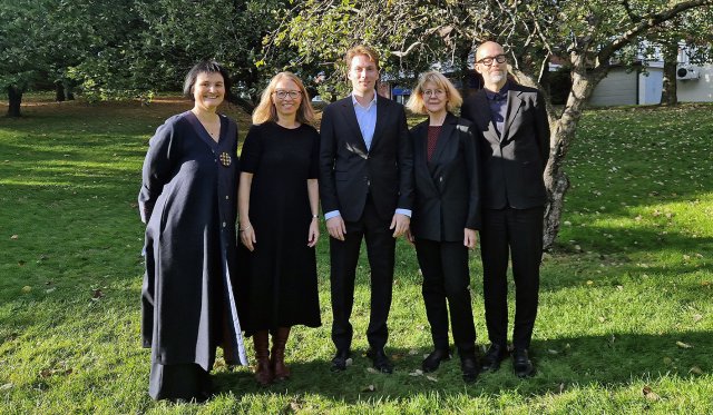 Gruppebilde av de fem som står på en rekke utendørs.