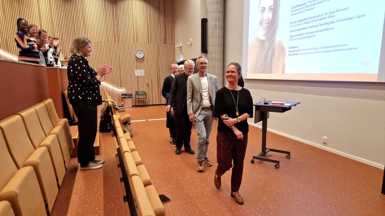 Torsteinson går ut fra disputasen mens publikum klapper.