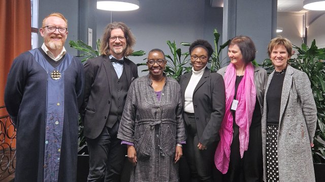 portrett av de seks stående på rekke innendørs.