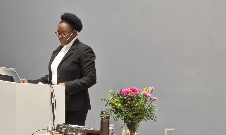 Elorm står og snakker foran talerstol.