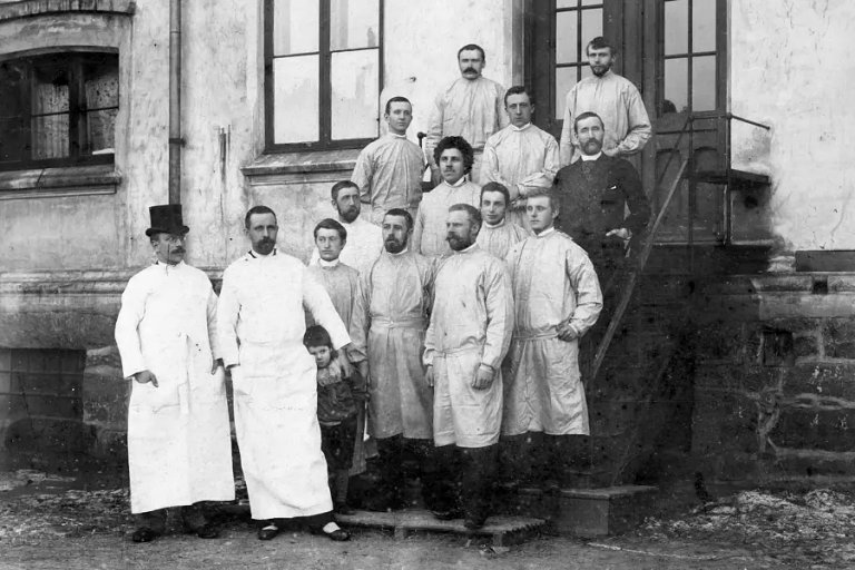 Gruppebilde tatt på trapp utenfor Diakonhjemmet. Alle studentene har hvit uniform.