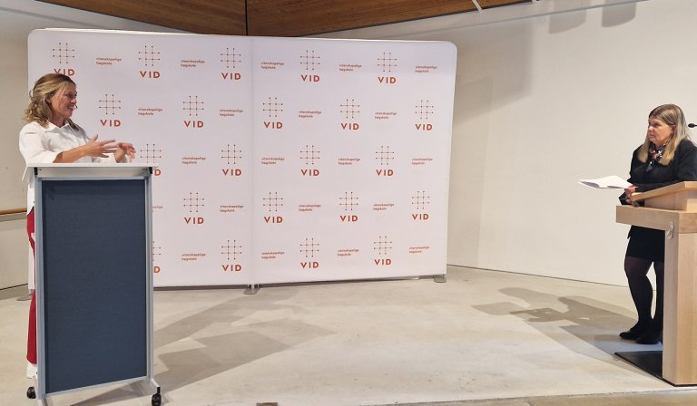 Kristin står på talerstol og snakker og gestikulerer.