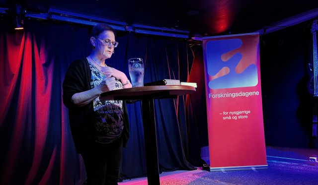 Hakalax står foran bord på scenen under forsker standup