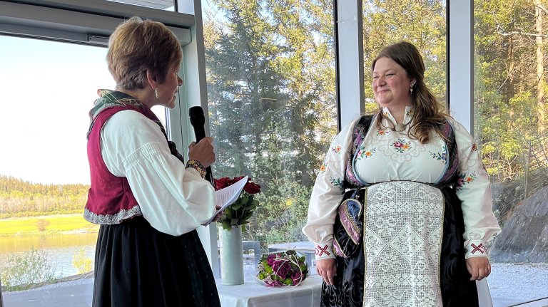 Jorunn Hov står og snakker i mikrofon til student på scene.