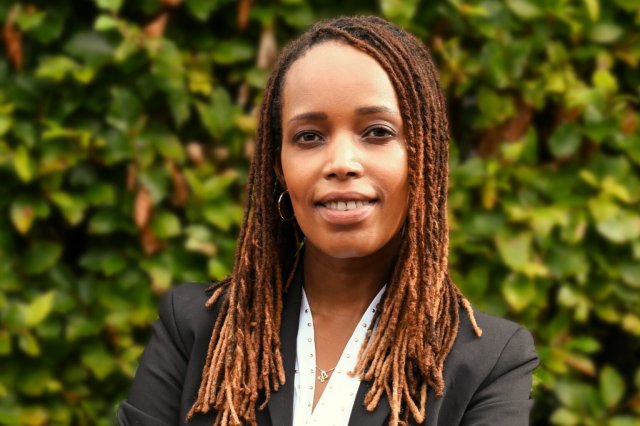 Francine Mbanza Jensen står iført svart blazer og hvit skjorte og smiler inn i kamera
