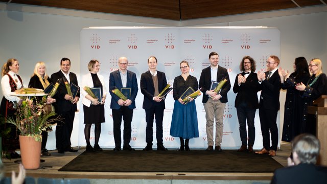 Portrett av en rad mennesker stående på scenen. Alle er festpyntet. 