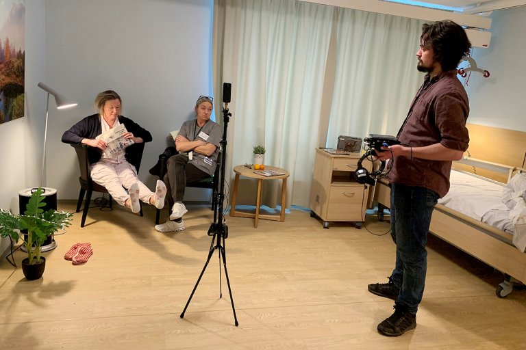 To damer sitter på hver sin stol i et rom som er rigget for videoopptak.
