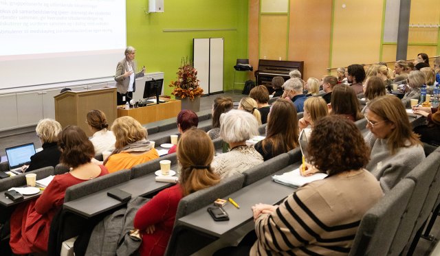 Bodil står og presenterer foran en fullsatt sal