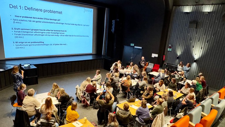 sal med forskere rundt bord og presentasjon på veggen. 