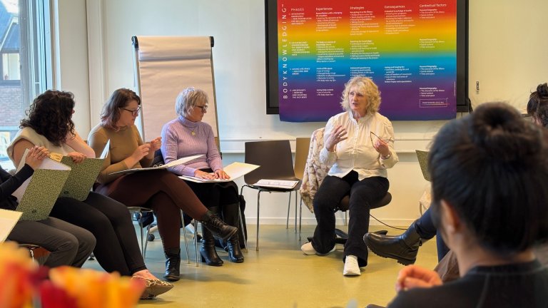 Heggdal sitter og snakker foran en ring med forskere