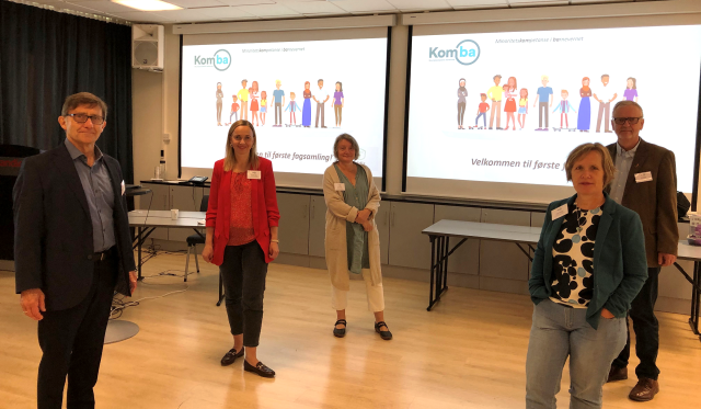 Fem personer oppstilt foran en lerret med presentasjoner