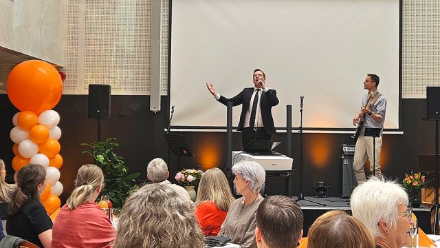 to menn står på scene foran publikum