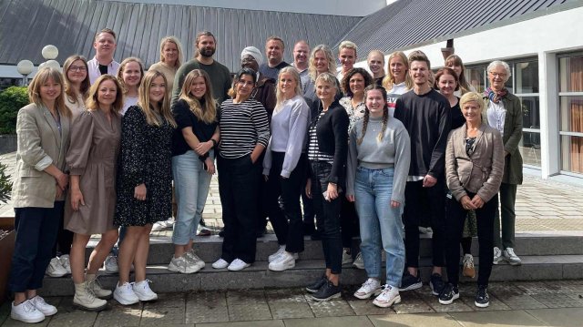 Oppstilt klassebilde utenfor hvit bygning av studentene ved Master i medborgerskap og samhandling
