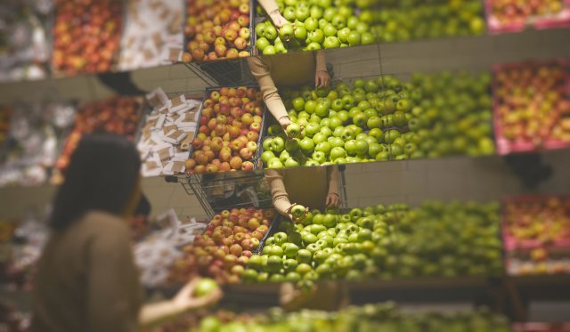 Kvinne sett bakfra foran esker med frukt