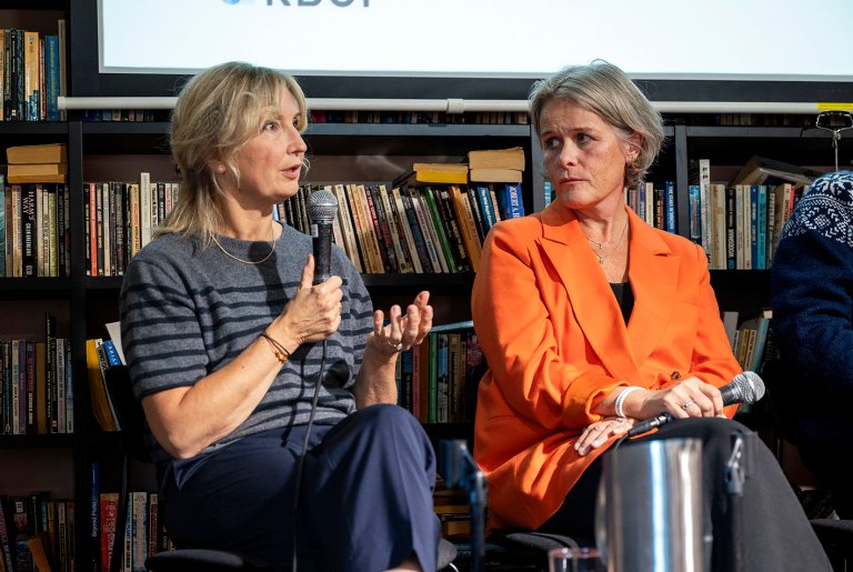 To kvinner sitter i paneldebatt og diskuterer.