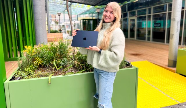 Bilde av en jente som holder en Macbook Air som hun vant da hun deltok i VID Utdanningsquiz. påsken 2024